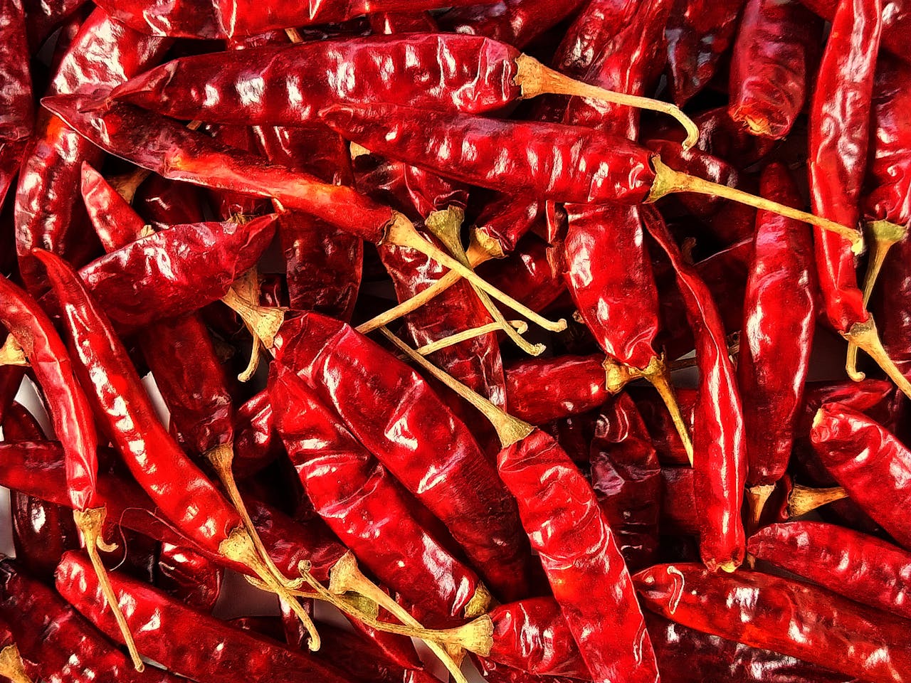 How to Check the Purity of Red Chilli Powder at Home High-resolution image of dried red chili peppers in a pile, showcasing texture and detail.