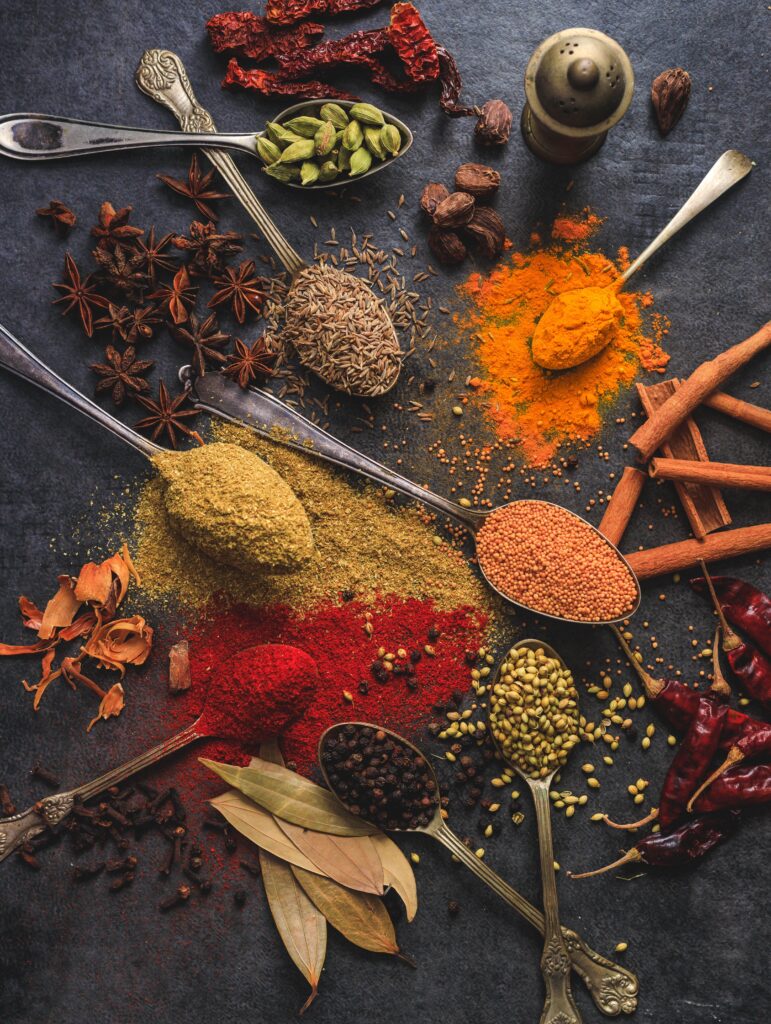 Gourmet Spice Blends Vibrant array of spices including turmeric, cumin, and chili arranged on a dark surface.