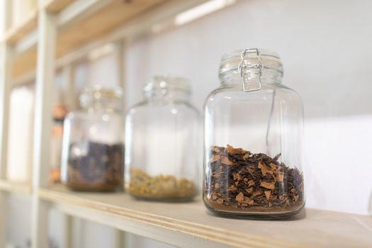 How to Store Spices Properly to Maintain Freshness and Flavor Close-up of glass jars filled with dried herbs on a wooden kitchen shelf.